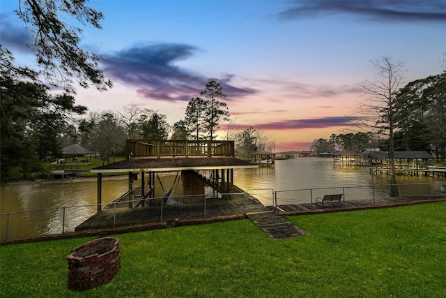 dock area featuring a water view, a yard, and fence