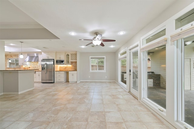 interior space featuring a tray ceiling, crown molding, recessed lighting, ceiling fan, and baseboards