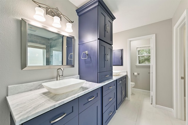 bathroom featuring tile patterned flooring, toilet, a sink, baseboards, and double vanity