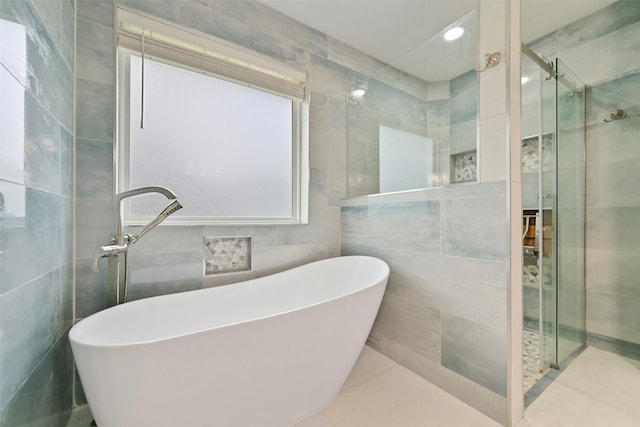 bathroom featuring tile walls, recessed lighting, a shower stall, a freestanding tub, and tile patterned floors