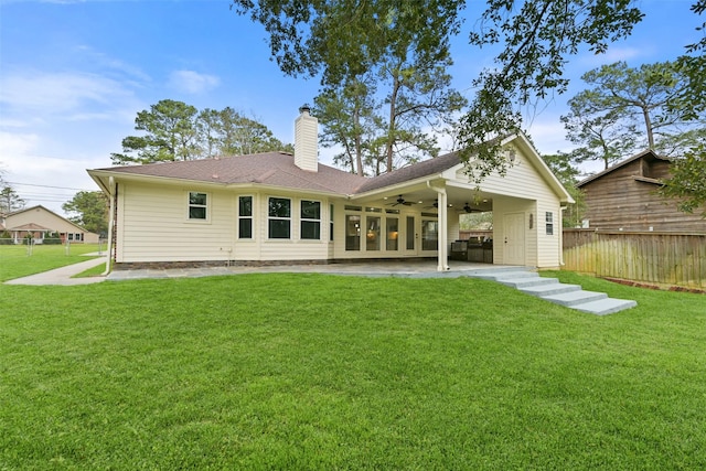 back of property with a lawn, ceiling fan, a chimney, fence, and a patio area