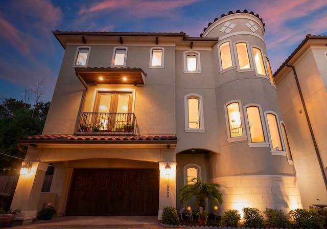 mediterranean / spanish home with a garage, driveway, a balcony, and stucco siding