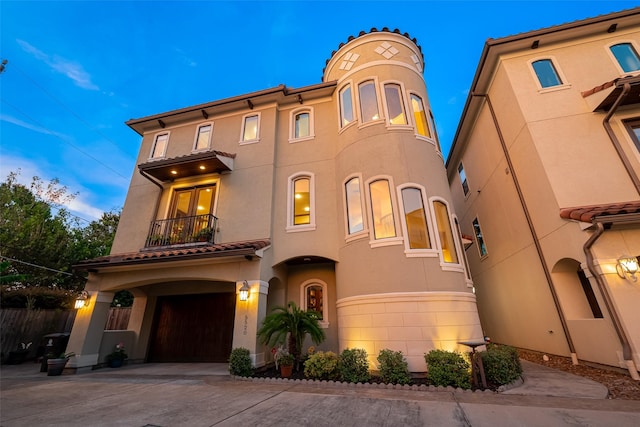 view of front of house with a balcony, driveway, an attached garage, and stucco siding