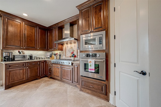 kitchen featuring stainless steel appliances, wall chimney range hood, light stone counters, and tasteful backsplash