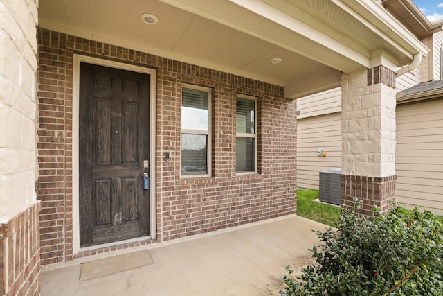 property entrance featuring brick siding and central air condition unit