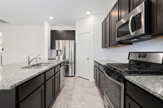 kitchen featuring visible vents, appliances with stainless steel finishes, light stone counters, a sink, and backsplash