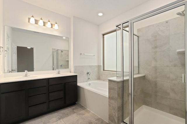 bathroom featuring a bath, a stall shower, double vanity, and a sink