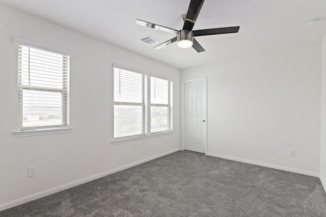 carpeted spare room featuring a ceiling fan, visible vents, and baseboards