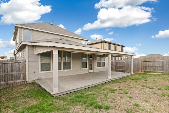 back of property featuring fence, a wooden deck, and a lawn