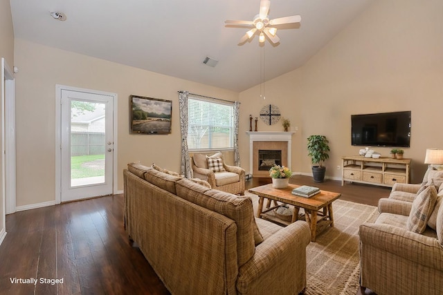 living area with plenty of natural light, dark wood finished floors, a ceiling fan, and a glass covered fireplace