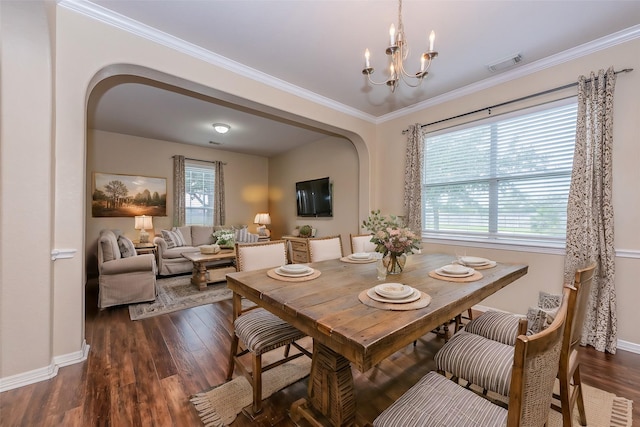 dining room featuring a healthy amount of sunlight, arched walkways, and dark wood finished floors