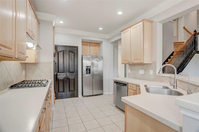 kitchen with appliances with stainless steel finishes, light brown cabinets, a sink, and ornamental molding