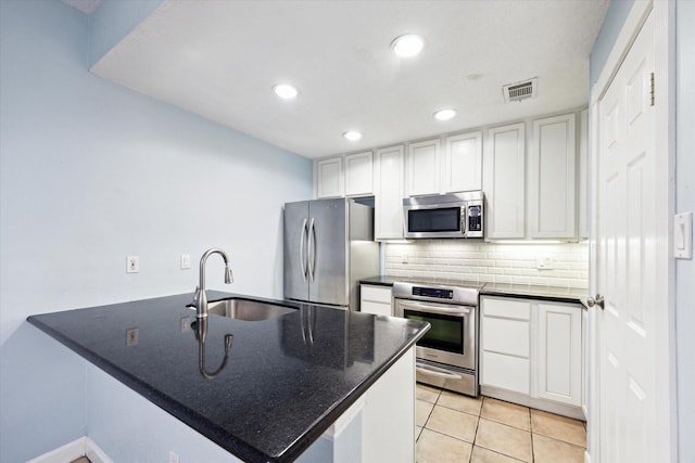 kitchen with stainless steel appliances, visible vents, decorative backsplash, a sink, and a peninsula