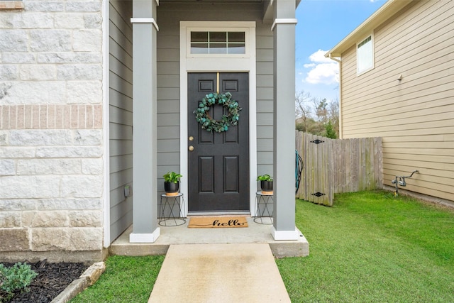 property entrance featuring fence and a lawn