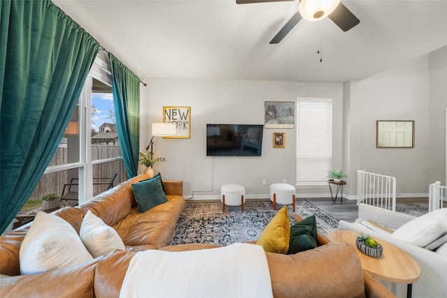 living area with a ceiling fan, wood finished floors, and baseboards