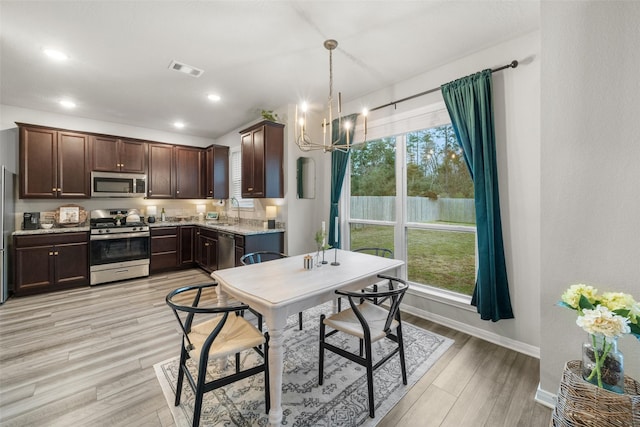 kitchen featuring light wood-style flooring, a sink, stainless steel appliances, dark brown cabinets, and a healthy amount of sunlight