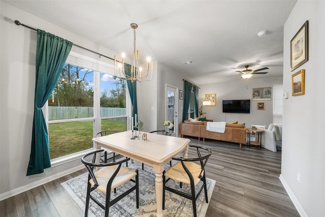 dining area with ceiling fan with notable chandelier, wood finished floors, and baseboards