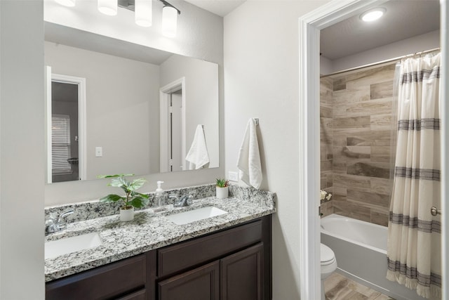 full bathroom featuring a sink, shower / bath combo with shower curtain, toilet, and double vanity