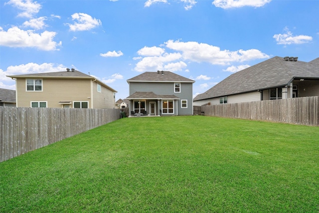 rear view of house featuring a lawn and a fenced backyard