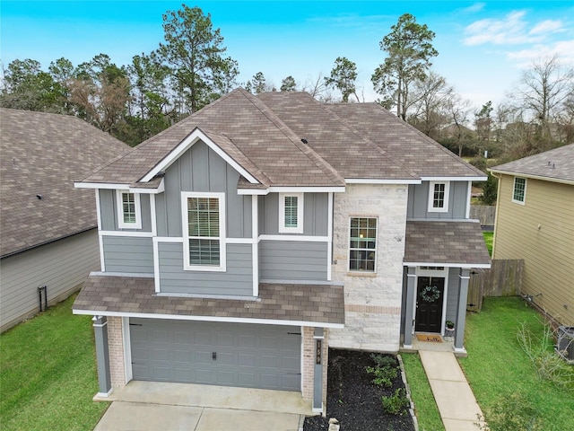 view of front of home featuring board and batten siding, fence, a front yard, a garage, and stone siding