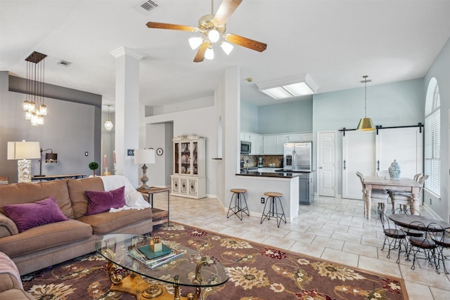 living area with light tile patterned floors, visible vents, baseboards, lofted ceiling, and ceiling fan with notable chandelier