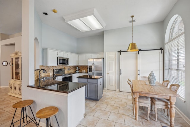 kitchen featuring visible vents, high vaulted ceiling, a sink, appliances with stainless steel finishes, and a peninsula