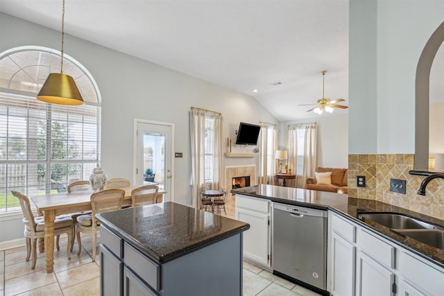 kitchen featuring a peninsula, a tile fireplace, a sink, dishwasher, and open floor plan