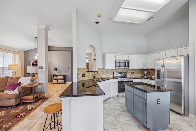 kitchen with a peninsula, backsplash, dark stone countertops, and appliances with stainless steel finishes