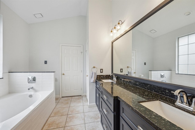 bathroom featuring a garden tub, vaulted ceiling, tile patterned floors, and a sink