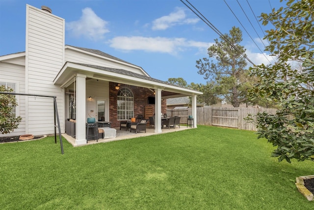 exterior space featuring a patio, fence, a lawn, brick siding, and an outdoor hangout area