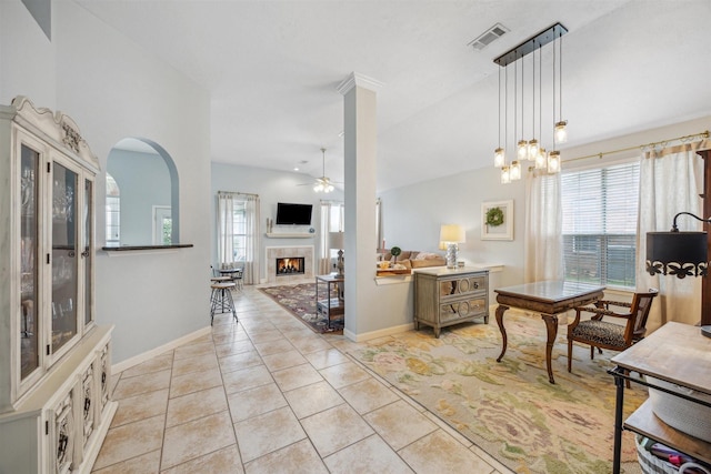 interior space featuring visible vents, ceiling fan, a tiled fireplace, vaulted ceiling, and light tile patterned floors