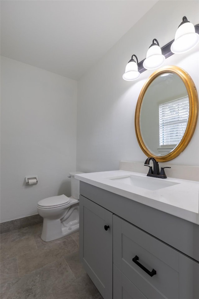 bathroom with toilet, baseboards, and vanity