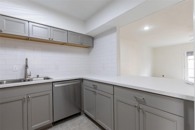 kitchen with a sink, tasteful backsplash, gray cabinets, and dishwasher