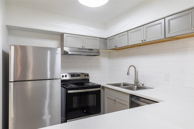 kitchen with stainless steel appliances, gray cabinets, a sink, and under cabinet range hood