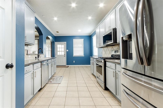 kitchen featuring light tile patterned floors, stainless steel appliances, decorative backsplash, and crown molding