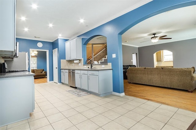 kitchen featuring appliances with stainless steel finishes, arched walkways, open floor plan, and crown molding