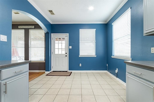 foyer featuring light tile patterned floors, baseboards, visible vents, and crown molding