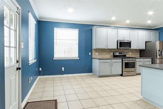 kitchen with light tile patterned floors, stainless steel appliances, baseboards, ornamental molding, and tasteful backsplash