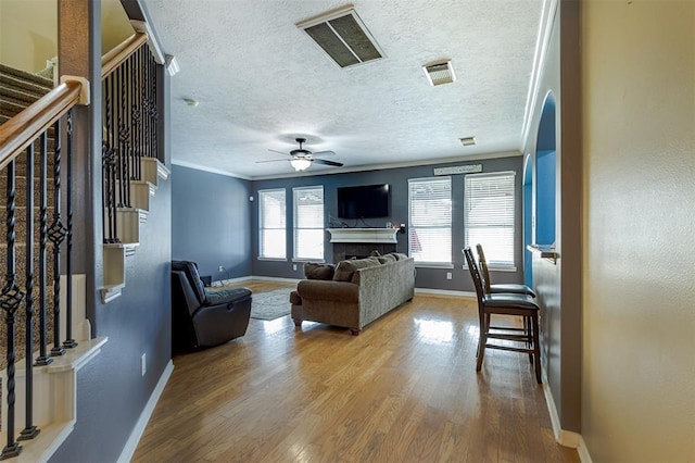 living area with ornamental molding, a fireplace, wood finished floors, and visible vents