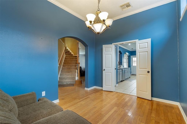 interior space featuring stairway, visible vents, light wood finished floors, and ornamental molding