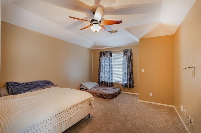 bedroom featuring visible vents, a raised ceiling, a ceiling fan, baseboards, and carpet