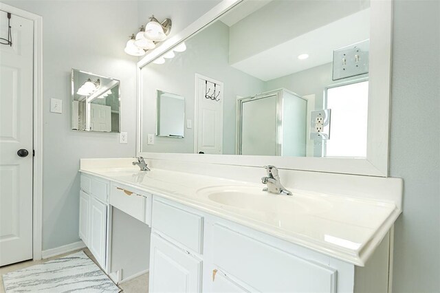 full bathroom featuring baseboards, double vanity, a sink, and a shower stall