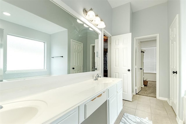 full bathroom with a sink, double vanity, tile patterned flooring, and baseboards