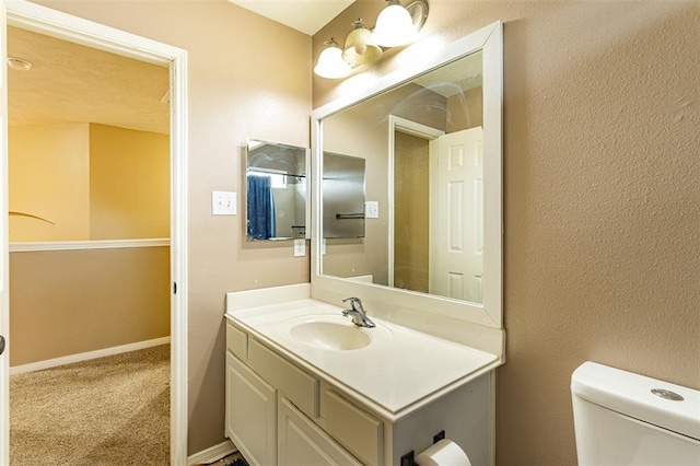 bathroom featuring toilet, vanity, and baseboards