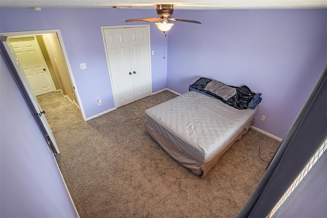 carpeted bedroom featuring a ceiling fan, a closet, and baseboards