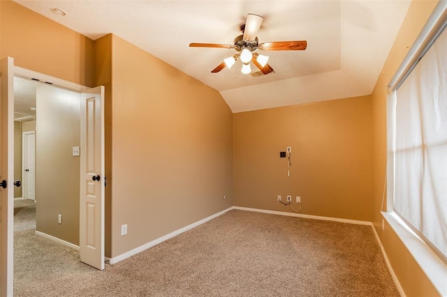 unfurnished room featuring vaulted ceiling, light colored carpet, ceiling fan, and baseboards