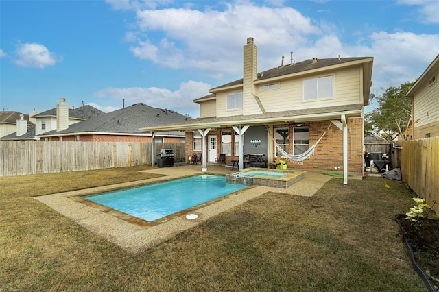 view of swimming pool with a yard, a patio, a pool with connected hot tub, a grill, and a fenced backyard