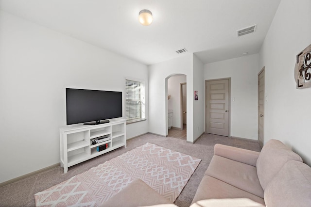 living room with arched walkways, visible vents, light carpet, and baseboards