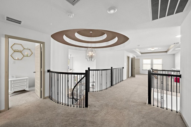 hallway featuring a raised ceiling, visible vents, and an upstairs landing