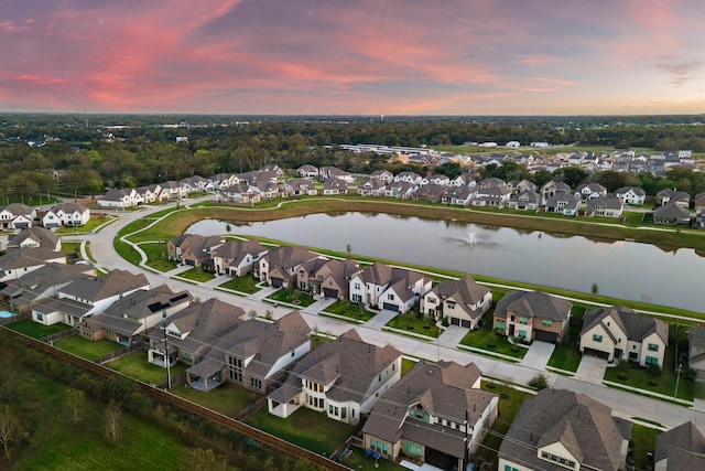 aerial view at dusk with a residential view and a water view